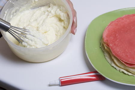 Cooking the pie with mascarpone cream. A woman prepares an impregnation of mascarpone for the cake.の写真素材