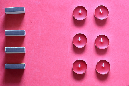 Decorative candles and matchboxes arranged in a row. On a pink background.の写真素材