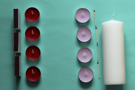 Decorative candles, matchboxes and matches are arranged in a row. On a mint background.の写真素材