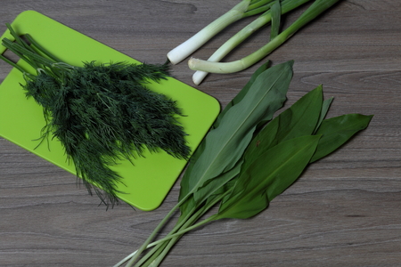 Fresh greens neatly laid out on the tabletop. Fragrant onions, dill and wild garlic. Next to the...