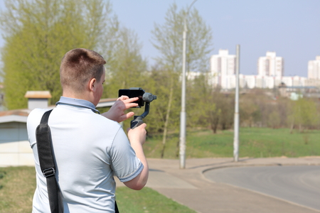 A young man videotaping on a smartphone. Uses gimbal to get smooth shots. Controls the recording by touching the screen.の写真素材