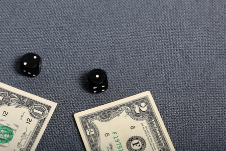 Black dice with white markings They lie on a surface covered with a coarse gray cloth. Near two...