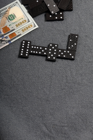 Domino knuckles on a surface covered with a coarse gray cloth. Nearby are two hundred dollar bills.の写真素材