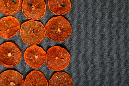 Tangerines are cut into slices and dried to decorate desserts. On a gray background.の写真素材