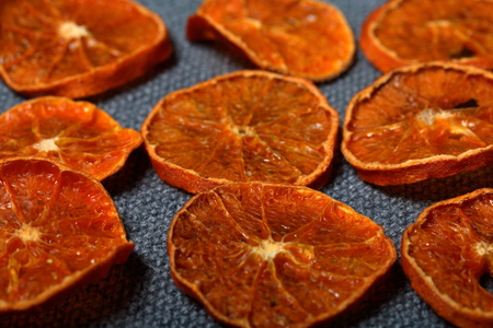 Tangerines are cut into slices and dried to decorate desserts. On a gray background.の写真素材