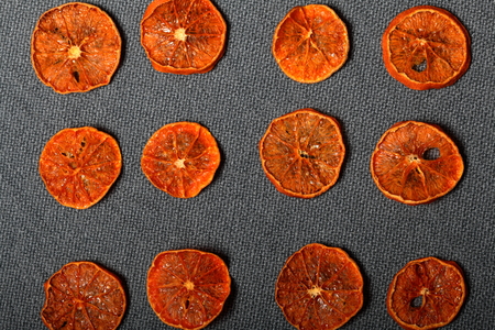 Tangerines are cut into slices and dried to decorate desserts. On a gray background.の写真素材