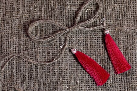 Earrings, tassels lie on a rough linen fabric. Near a bow of linen thread.の写真素材