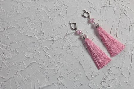 Earrings tassels. They lie on the surface covered with white decorative plaster.の写真素材