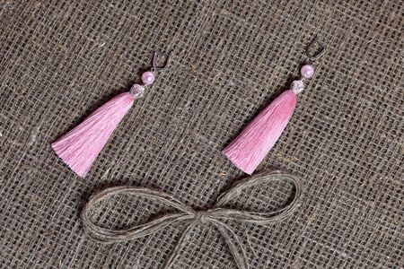 Earrings, tassels lie on a rough linen fabric. Near a bow of linen thread.の写真素材