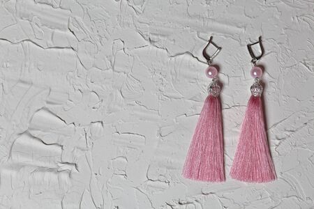 Earrings tassels. They lie on the surface covered with white decorative plaster.の写真素材