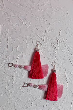 Earrings tassels. They lie on the surface covered with white decorative plaster.の写真素材