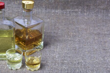 Bottled bottles of strong alcohol. From transparent glass, a square form. Near the stack with a...
