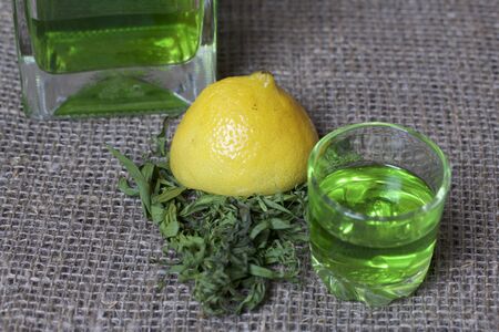 Strong tincture on tarhuna in a transparent rectangular bottle. Drink bright green poured into a...