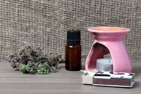 Aromatherapy lamp with candles and accessories. Oil in a bottle and matches. Nearby lies a bunch of dry thyme.の写真素材