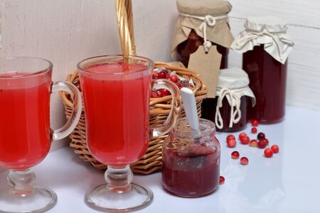 Homemade blanks. Cranberry jam in jars and glasses with cranberry juice. One can is open, it has a...