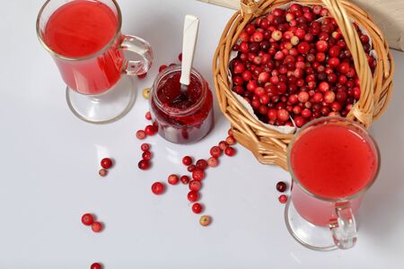 Homemade blanks. Cranberry jam in jars and glasses with cranberry juice. Several berries are...