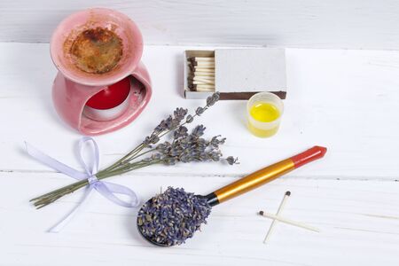 A bunch of lavender for aromatherapy and plant flowers in a spoon. Nearby is the aroma lamp. Oil is poured into the cap. Natural pharmacy. Aromatherapy with natural oils.の写真素材