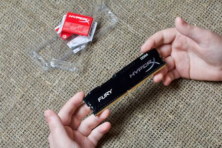 MINSK, BELARUS - NOVEMBER 25, 2019: A man is holding a bar of RAM HyperX Fury 8GB DDR4. Nearby lies...