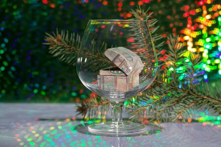 An open chest with gifts stands in a wine glass. Against the background of a fir branch and rainbow bokeh.の写真素材
