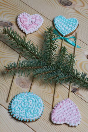 Spicy gingerbread cookie on a stick. Garnished with multicolored sugar glaze. Lies on pine boards. Near a branch of spruce.の写真素材