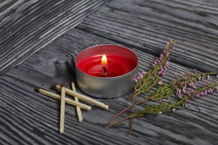 Burning candle on brushed boards. Near heather and burnt matches.の写真素材