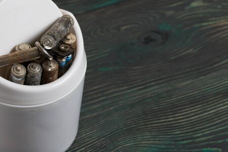 Waste bin. It contains finger-type batteries coated with corrosion. Against the background of...