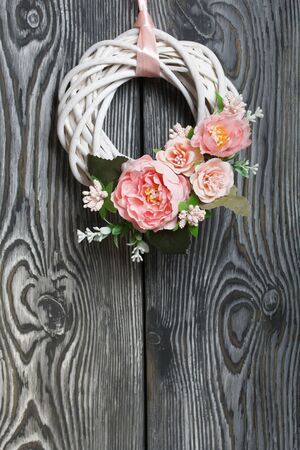 Decorative wreath of twigs of vines. Painted in white. Decorated with decorative flowers. Against the background of brushed boards painted in black and white.の写真素材