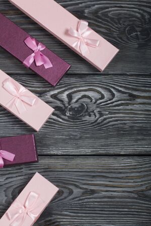 Cardboard boxes with gifts. Pink and lilac, decorated with ribbon bows. Lying on the background of brushed pine boards.の写真素材