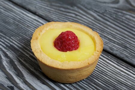 Tartlets with lemon Kurd. Decorated with raspberries. They lie on black brushed pine boards.の写真素材