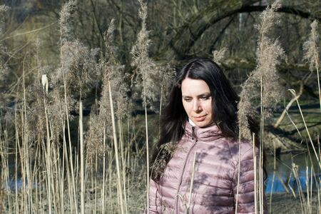 A girl walks through the spring park. It stands among tall dry grass.の写真素材