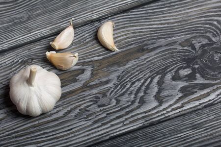 Head of garlic, a few cloves of garlic. They lie on the surface of brushed pine boards.の写真素材
