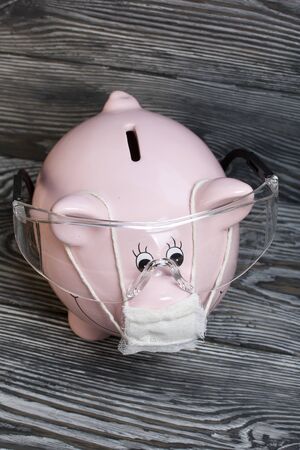 Ceramic piggy bank in pink. With a gauze bandage. Savings on treatment and life during an epidemic.の写真素材