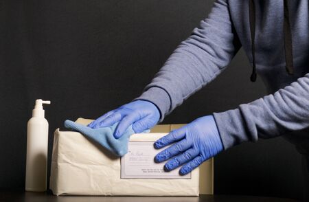 Delivery of correspondence during the period of self-isolation. A man in rubber gloves disinfects...