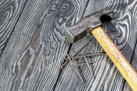 An old hammer and several nails of different sizes. On pine brushed boards painted black. World Labor Day.の写真素材