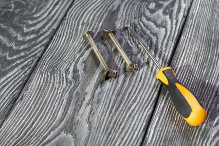 Metal bolts, wing nuts and screwdriver. On pine brushed black-painted boards. World Labor Day.
