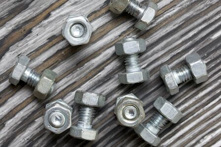 A handful of metal bolts with screwed nuts. They lie on pine brushing boards painted black. World Labor Day.の写真素材