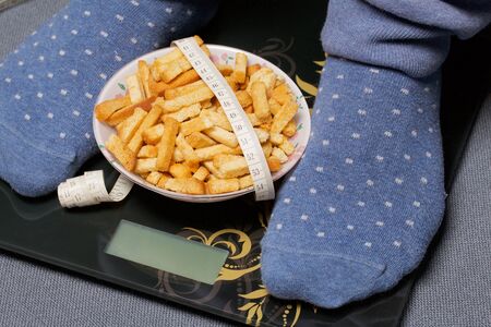 A man is standing on the floor scales. Near a cup with crackers for beer and a measuring tape. World...