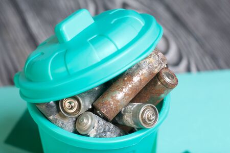 Trash can with lid filled with waste batteries. The batteries are covered with corrosion. Close-up shot. Symbol of environmental protection day.の写真素材
