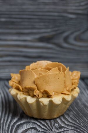Half a cake decorated with butter cream flowers. The cream has a caramel color. On brushed pine boards painted black.の写真素材
