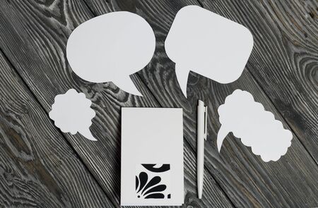 Speech bubbles on a background of brushed pine boards. Blogger notes pad and pen.の写真素材