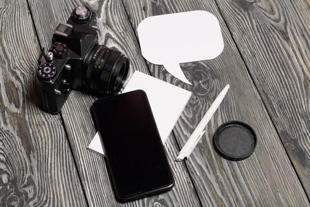 Smartphone and camera blogger. Near a notebook and pen. Around speech bubbles. Against the...