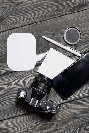 Smartphone and camera blogger. Near a notebook and pen. Around speech bubbles. Against the background of brushed pine boards.の写真素材