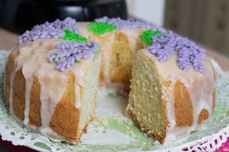 Lavender Cupcake. Sugar coated. Decorated with lavender glaze flowers. A small piece is cut off.