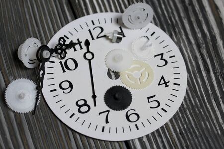 Watch mechanism details. Gears, arrows and dial. On brushed pine boards.