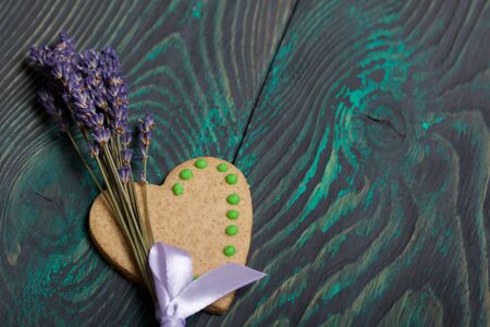 Gingerbread cookies decorated with glaze. Gingerbread cookies in the form of a heart. Near a bouquet of lavender. On brushed pine boards.の写真素材