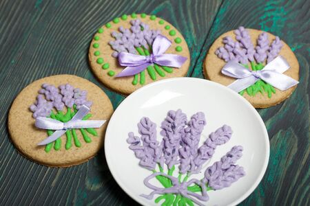 Gingerbread cookies decorated with glaze. Some are decorated with a ribbon tied to a bow. Near a saucer with a pattern of glaze. On brushed pine boards.の写真素材