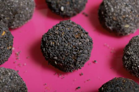 Plate with sweets coated with sesame seeds. Candies in the form of balls lie on a plate. On brushed pine boards.の写真素材