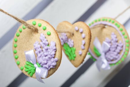 Gingerbread cookies decorated with glaze. On some ribbons tied to a bow. Gingerbread cookies are round and in the shape of a heart. Hanging on a rope.の写真素材