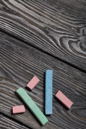 Pieces of chalk for drawing, different colors. They lie on pine boards painted with white and black...