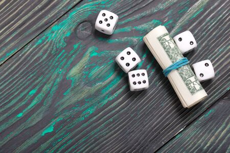 Dice are white. Near dollars rolled up in a tube. On brushed pine boards.の写真素材